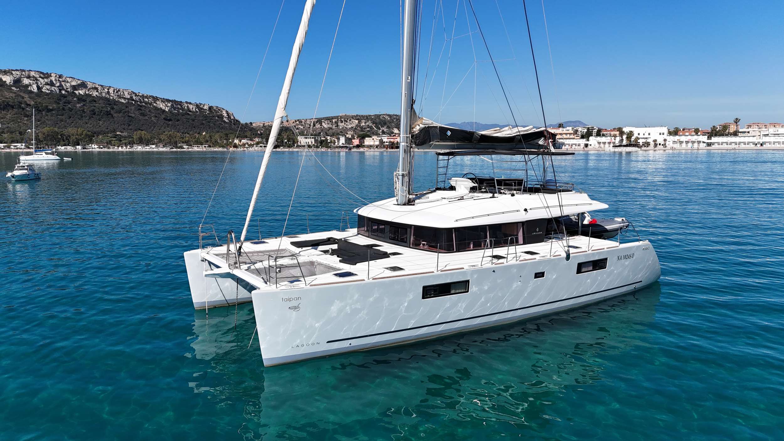 Launched in 2019 and refitted in 2024, Taipan is a Lagoon 560 S2, an ideal getaway for those seeking luxury, comfort and adventure. Taipan has 5 guest cabins, 1 king-size, 2 queen-size cabins and 1 pullman berths cabin, all en-suite, accommodating up to 10 guests.

Elegant, uncluttered, and minimalist, with a focus on large windows, natural materials, and neutral colors. This catamarans is the perfect choice to spend an amazing time at sea and explore the Sardinian and Corse Cristal waters.

Guests will have a hard time deciding between the aft cockpit, the spacious flybridge, and the forward dinette:
There is a large dining table in the aft cockpit, which can easily accomodate up to 10 guests. All around, a daybed relax area where enjoy the navigation. Just off the back of the aft dining area a wide electro-hydraulic bathing platform stores the fast tender, which is powered by 50hp. During the day the platform doubles as a water toy area, where we can launch the seabobs, SUP, Kayaks, kneeboard, wakeboard or even set up a day lounge for sunbathing and cocktails.

A spiral staircase brings you to the flybridge, fitted with a sun awning area, a small fridge and a table to enjoy Italian Style aperitifs with an amazing 360 degrees view. All sailing lines lead to the base of the mast, an ideal spot for guests to join in on the sailing action.

The forward dinette it's an amazing sunbath area.The two big nets will allow you to fully observe the sea and experience it during the navigation. 

The main saloon has a fully equipped galley, where the clients can see their Hostess/cook while preparing our specialities. On the opposite side, an L-shaped sofa with a coffe table will allow you to relax while watching the 43